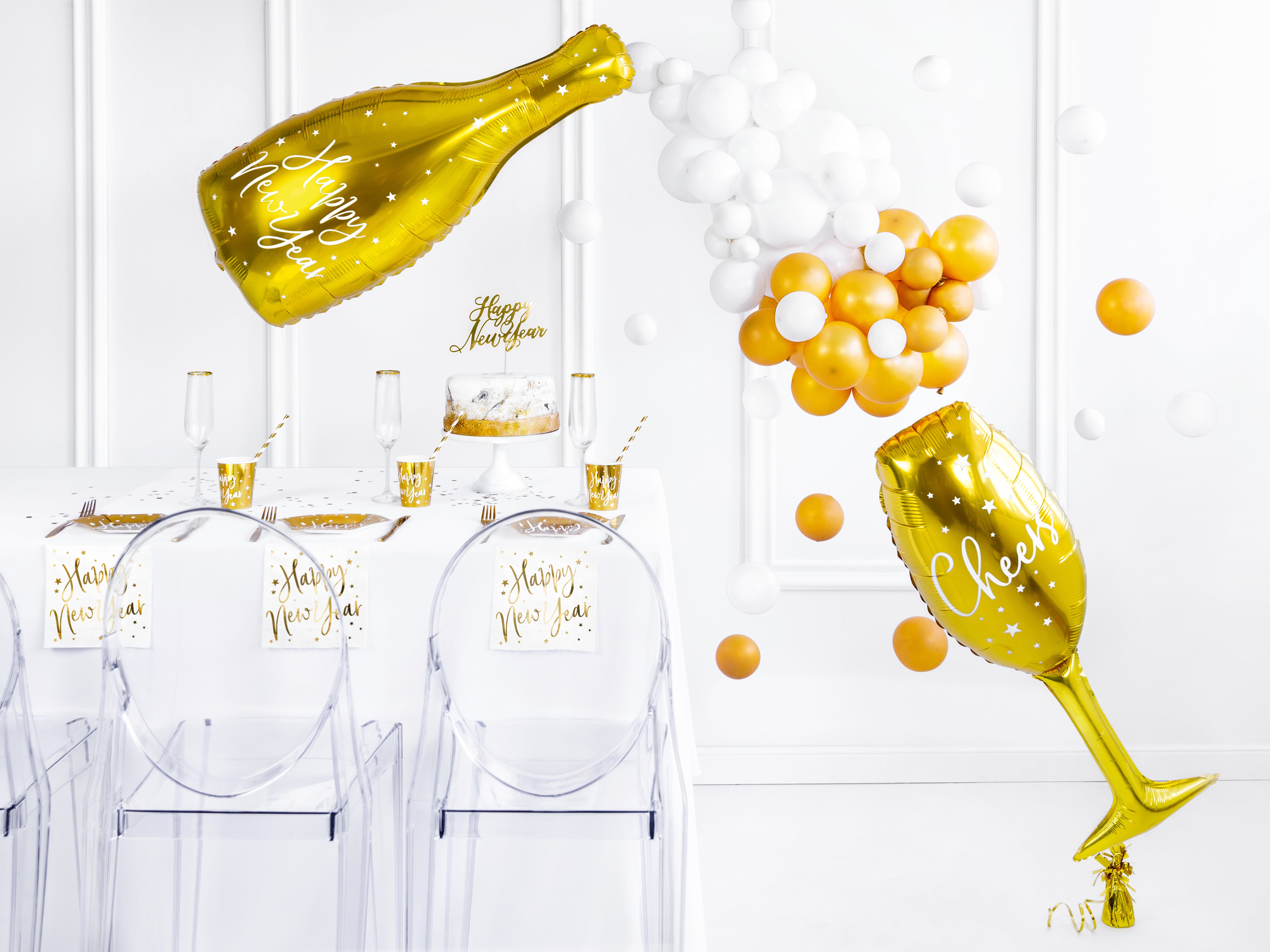 Elegant white and gold NYE party decor featuring gold plates, champagne balloons, and festive cups.