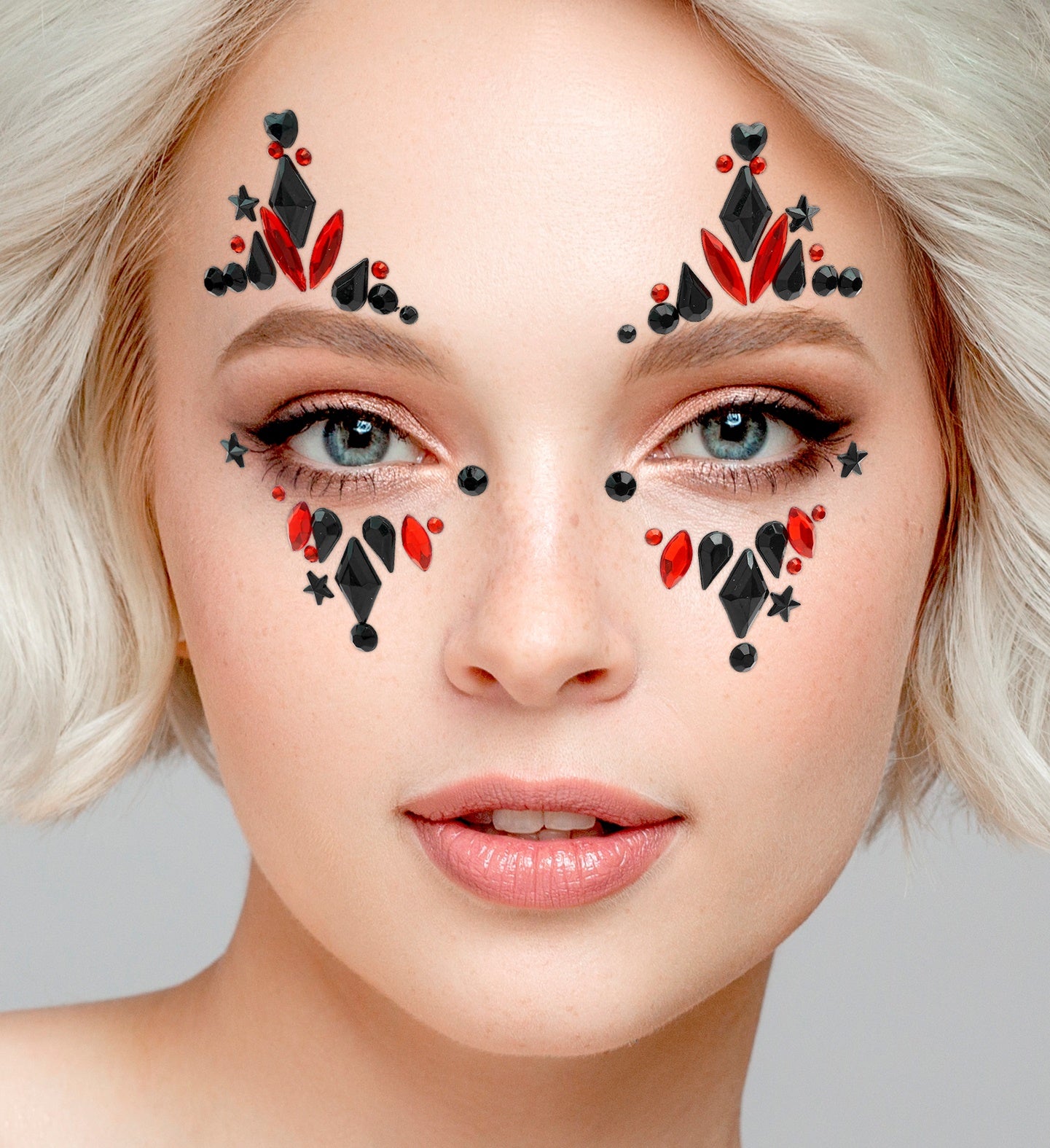 Close-up of red and black harlequin face jewels applied above and below the eyes for a professional costume finish.