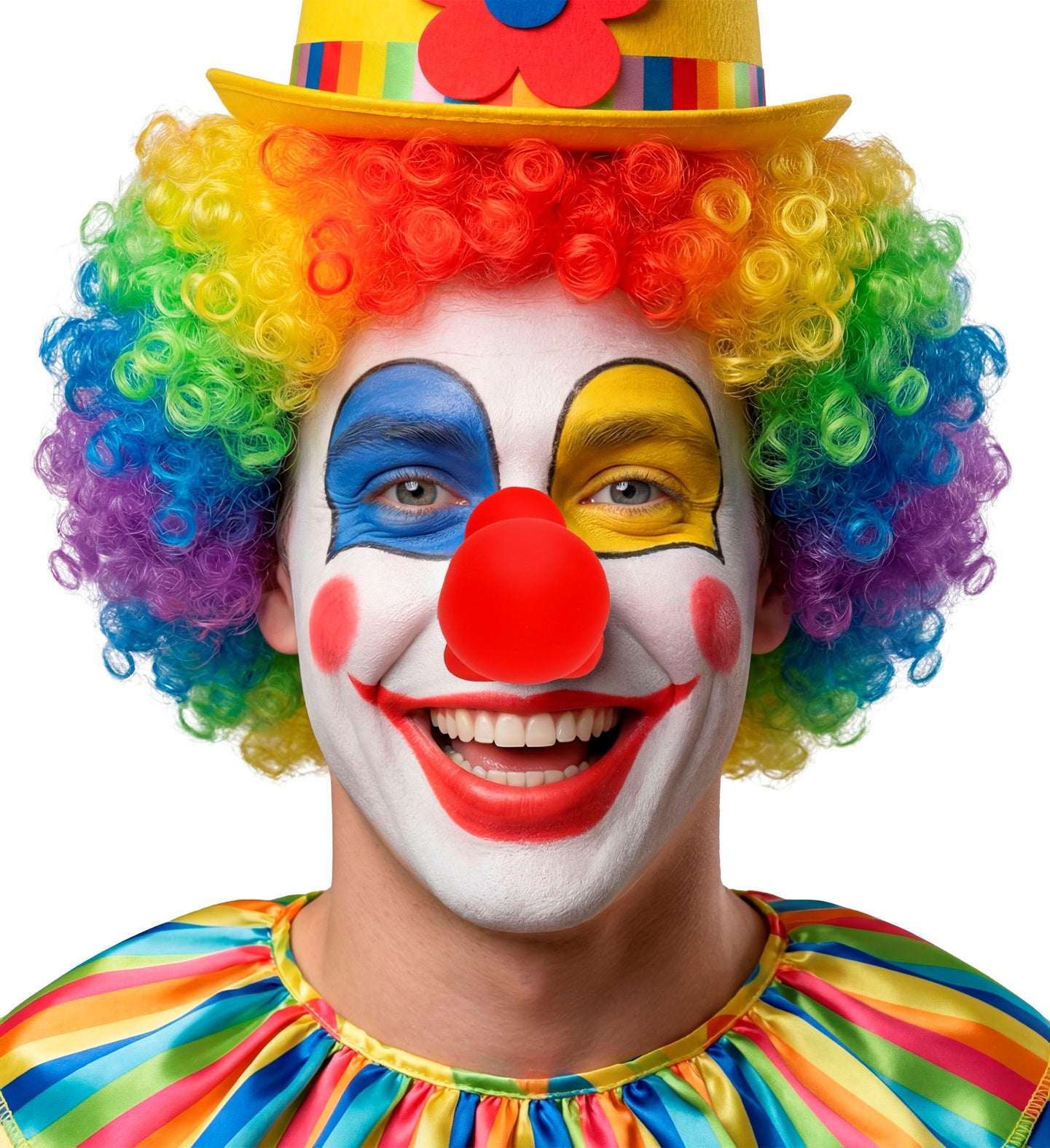 A smiling model wearing vibrant circus clown makeup, a rainbow curly wig, a yellow hat with a flower, and a bright red squeaking clown nose.