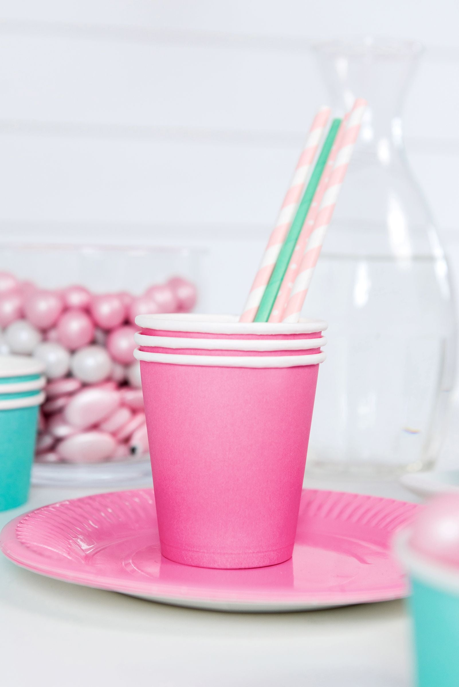 Light pink striped paper straws placed in a pink party cup on a decorated dessert table.