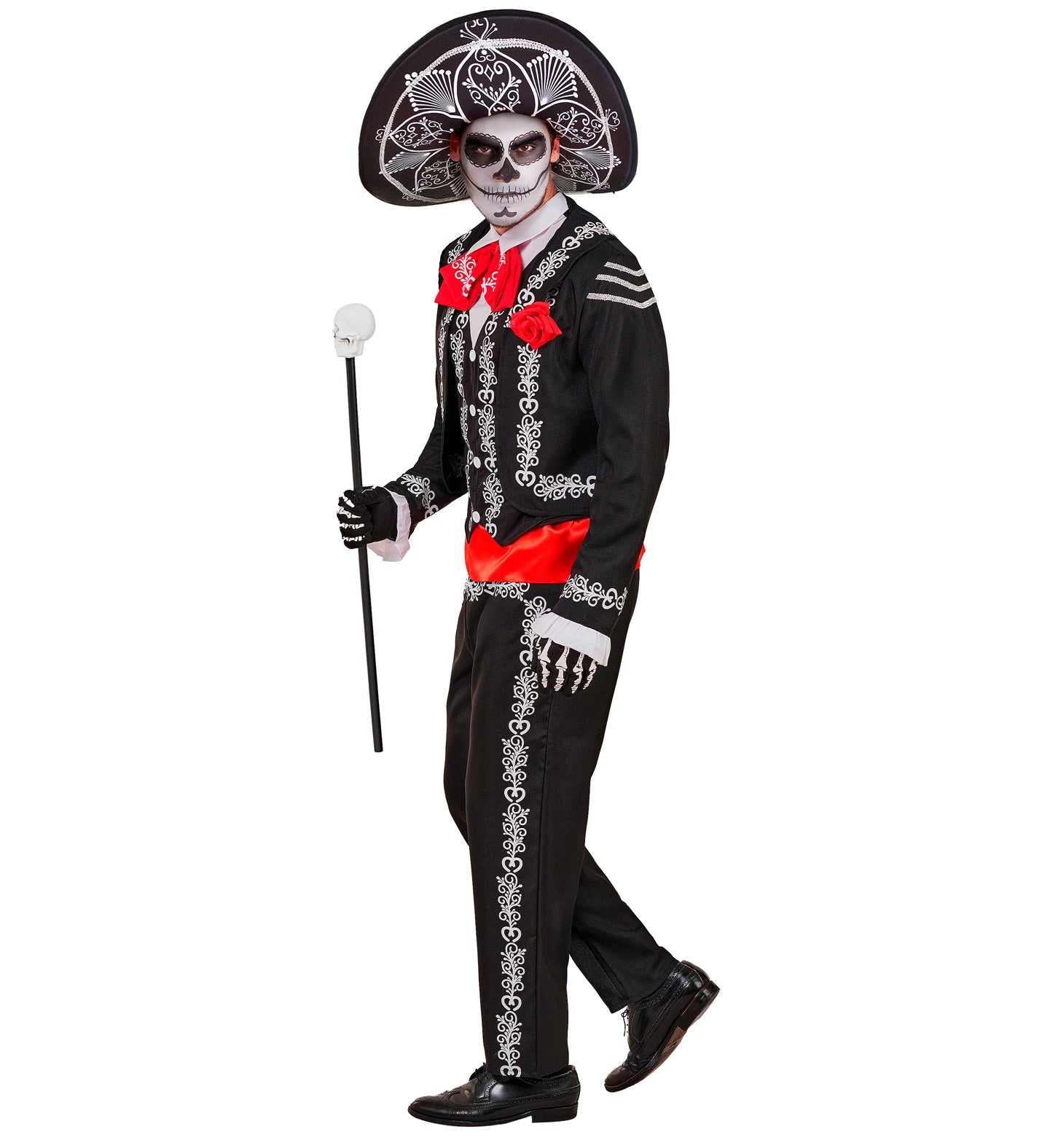 A side-profile view of a model wearing a black and white Day of the Dead Mariachi costume and sombrero, painted with sugar skull makeup and holding a black cane with a white skull handle.