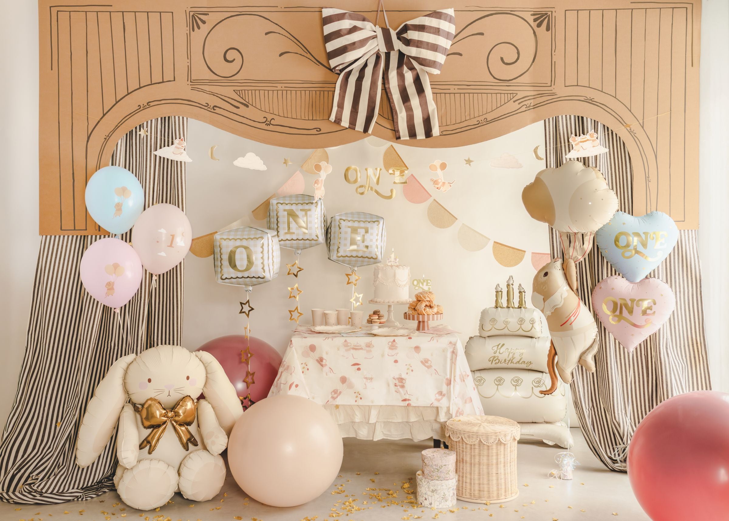 A grand woodland-themed 1st birthday setup featuring a dessert table with a mice tablecloth, a large bunny and mouse, 'ONE' balloon blocks, and pastel balloons.
