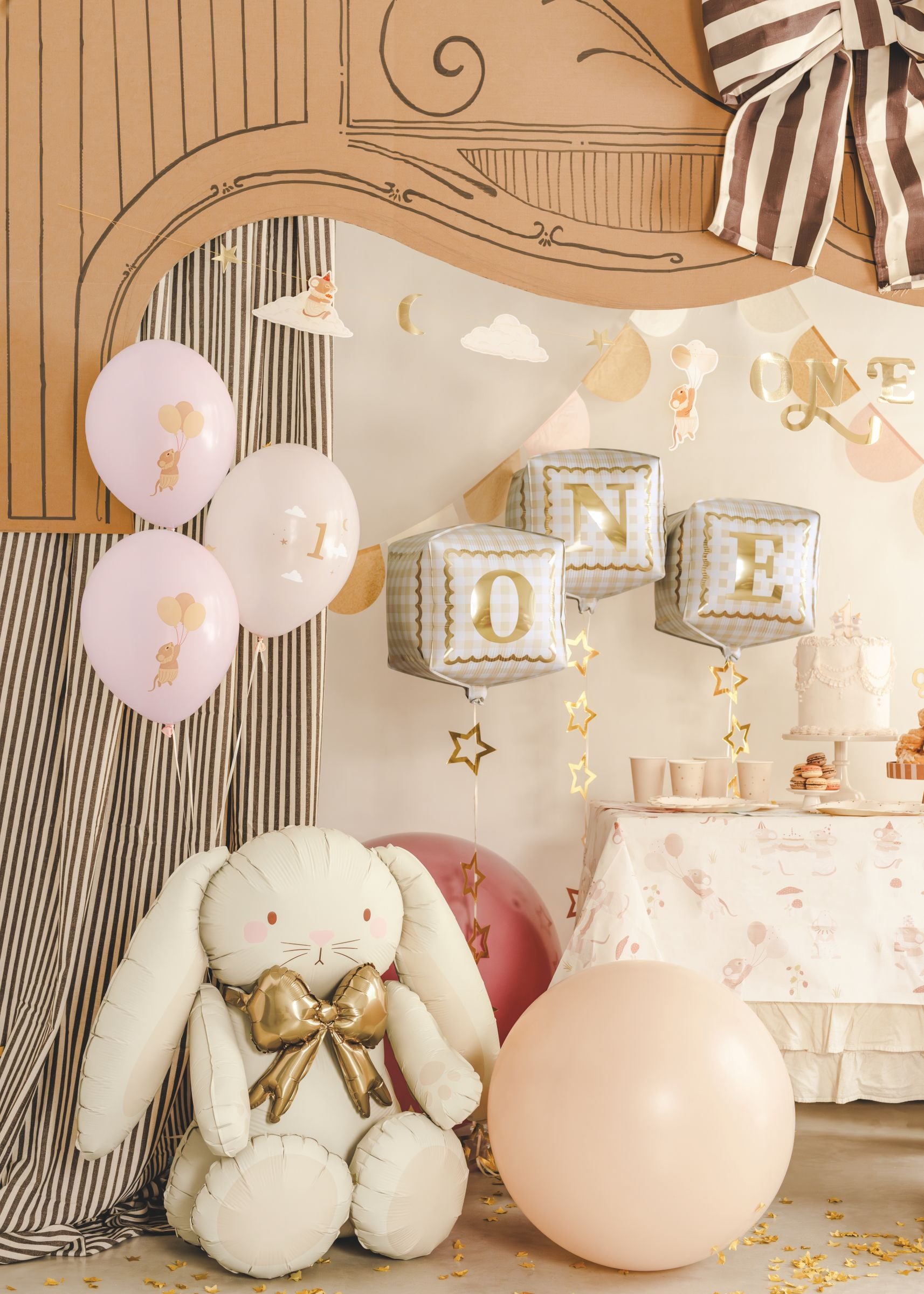 Close-up of a whimsical 1st birthday party setup showing a plush bunny, pastel pink mice balloons, and three gingham cube foil balloons spelling 'O-N-E'.