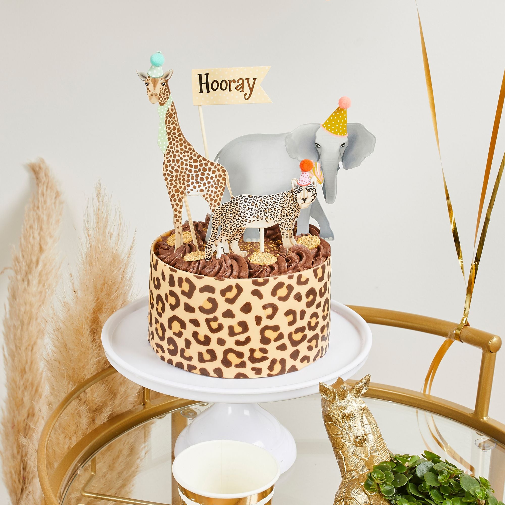 Leopard print cake with animal toppers on a white plate against a light background