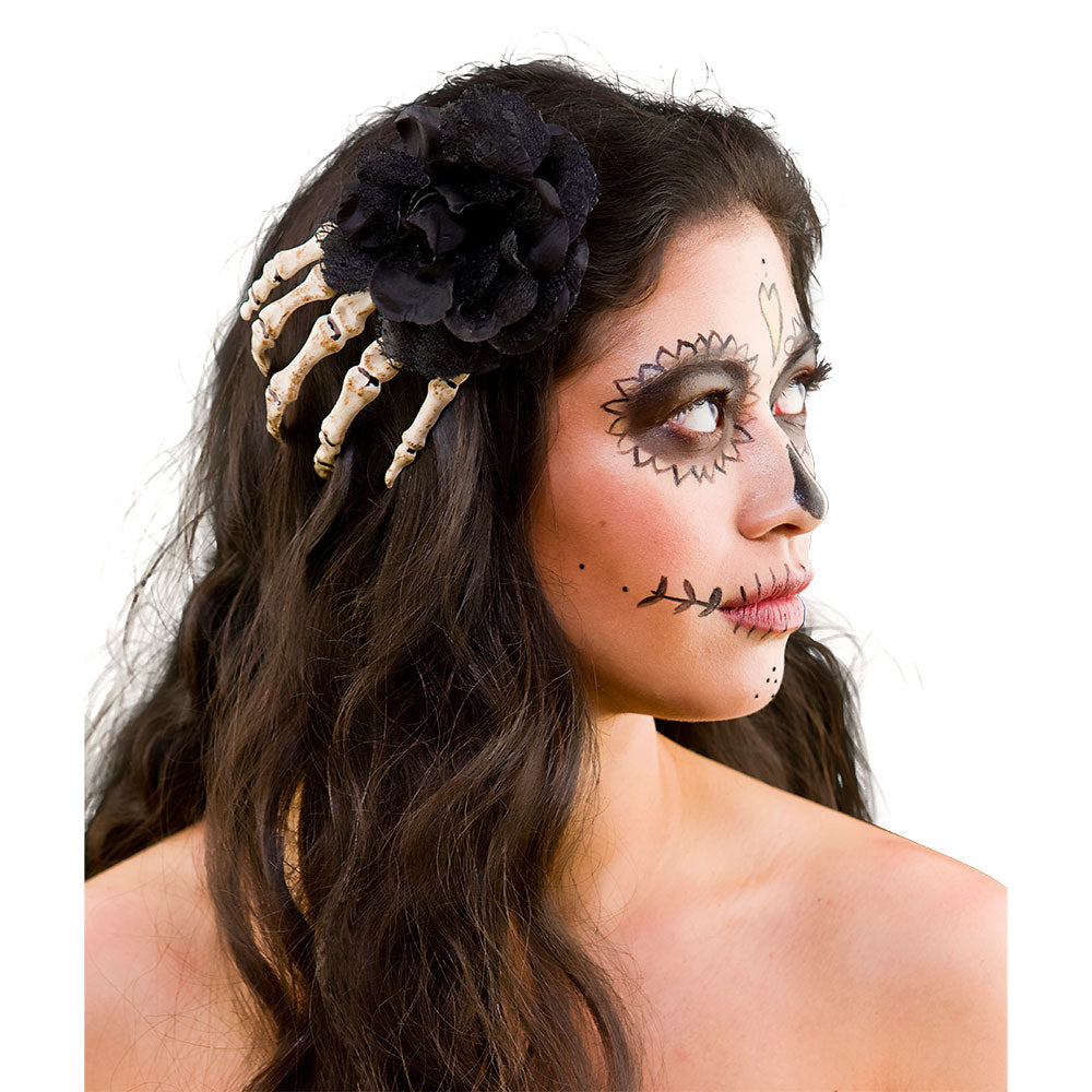 Woman with skeleton hand hair accessory and Day of the Dead makeup on a white background