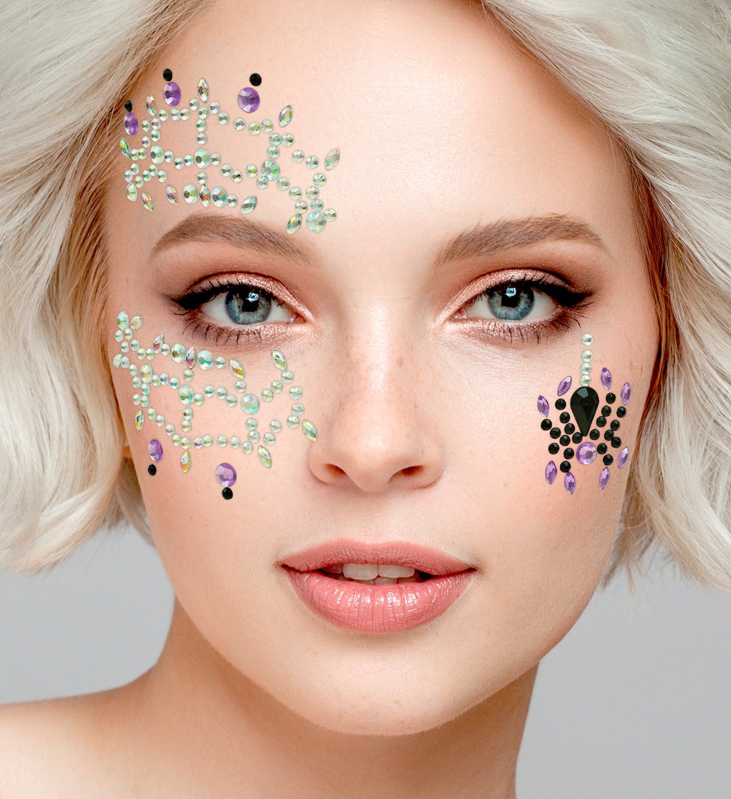 Close-up of iridescent spiderweb face jewels and a black and purple jeweled spider applied for a spooky costume look.
