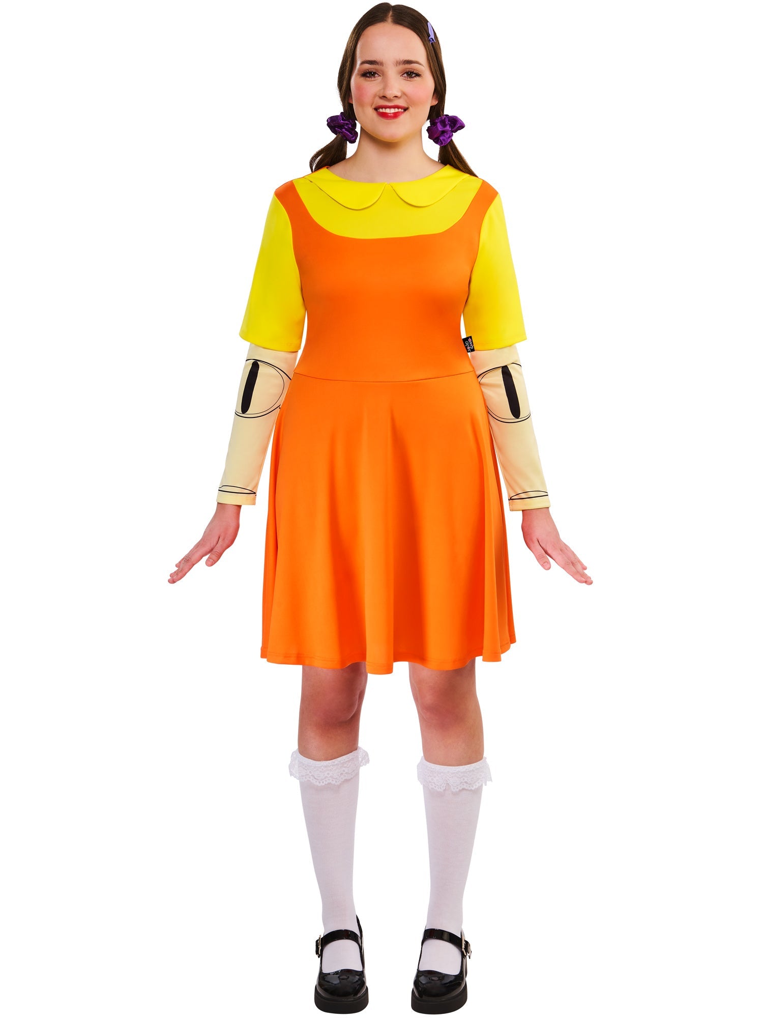 Front view of a woman wearing the Game Doll costume, including the orange and yellow dress and white frilly socks, with a serious expression