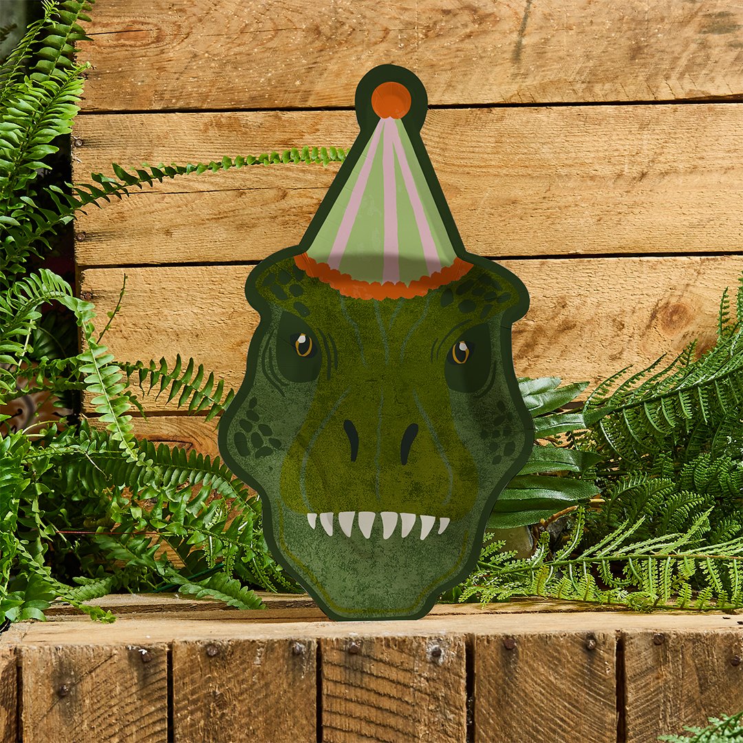 A dinosaur-shaped party plate displayed against a wooden background with green ferns, creating a legendary jungle vibe.