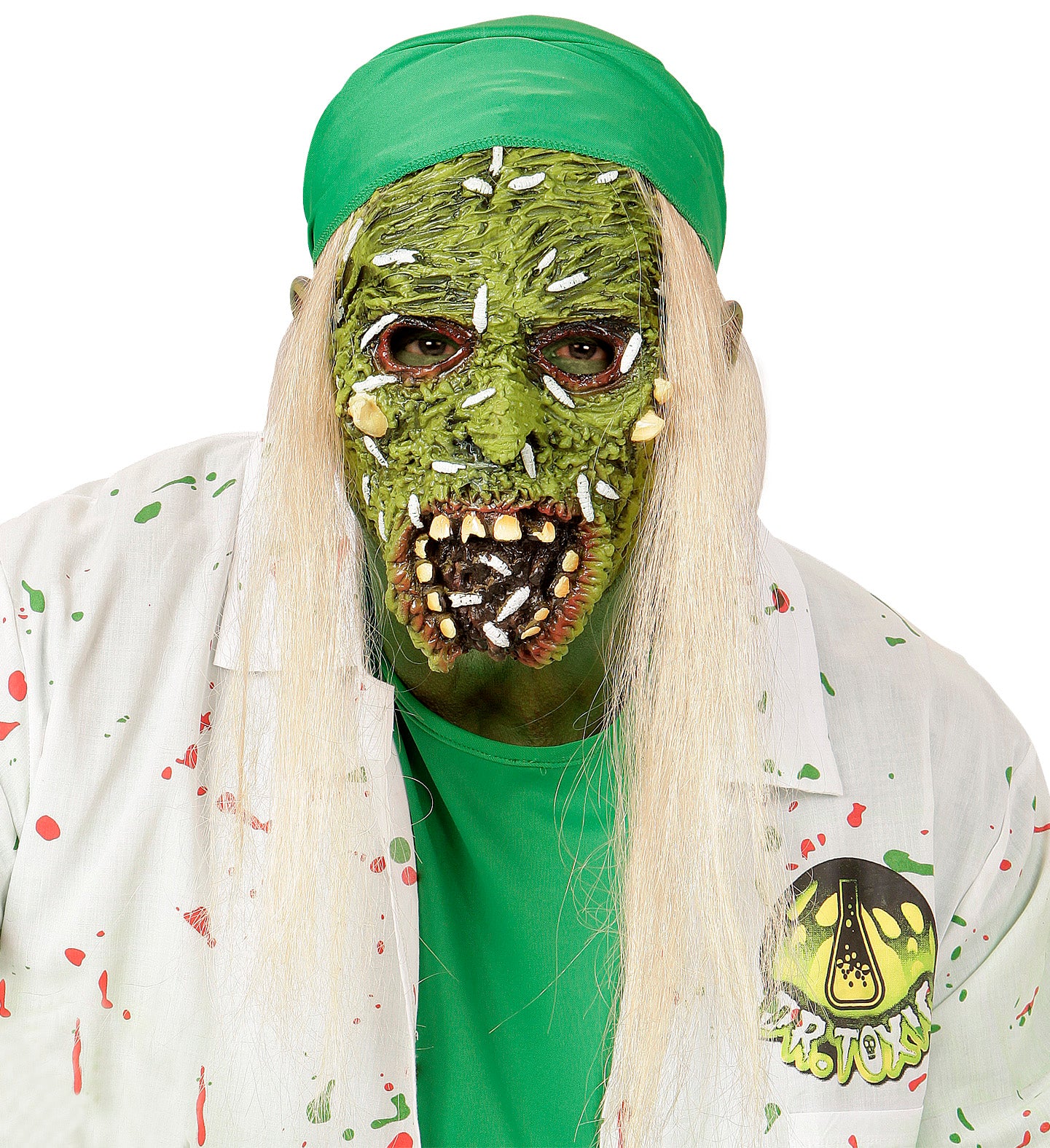 A close-up of a child's head and shoulders wearing a green, gruesome-looking zombie overhead latex mask with long white hair and a green head wrap. The person is also wearing a white lab coat splattered with red and green paint.