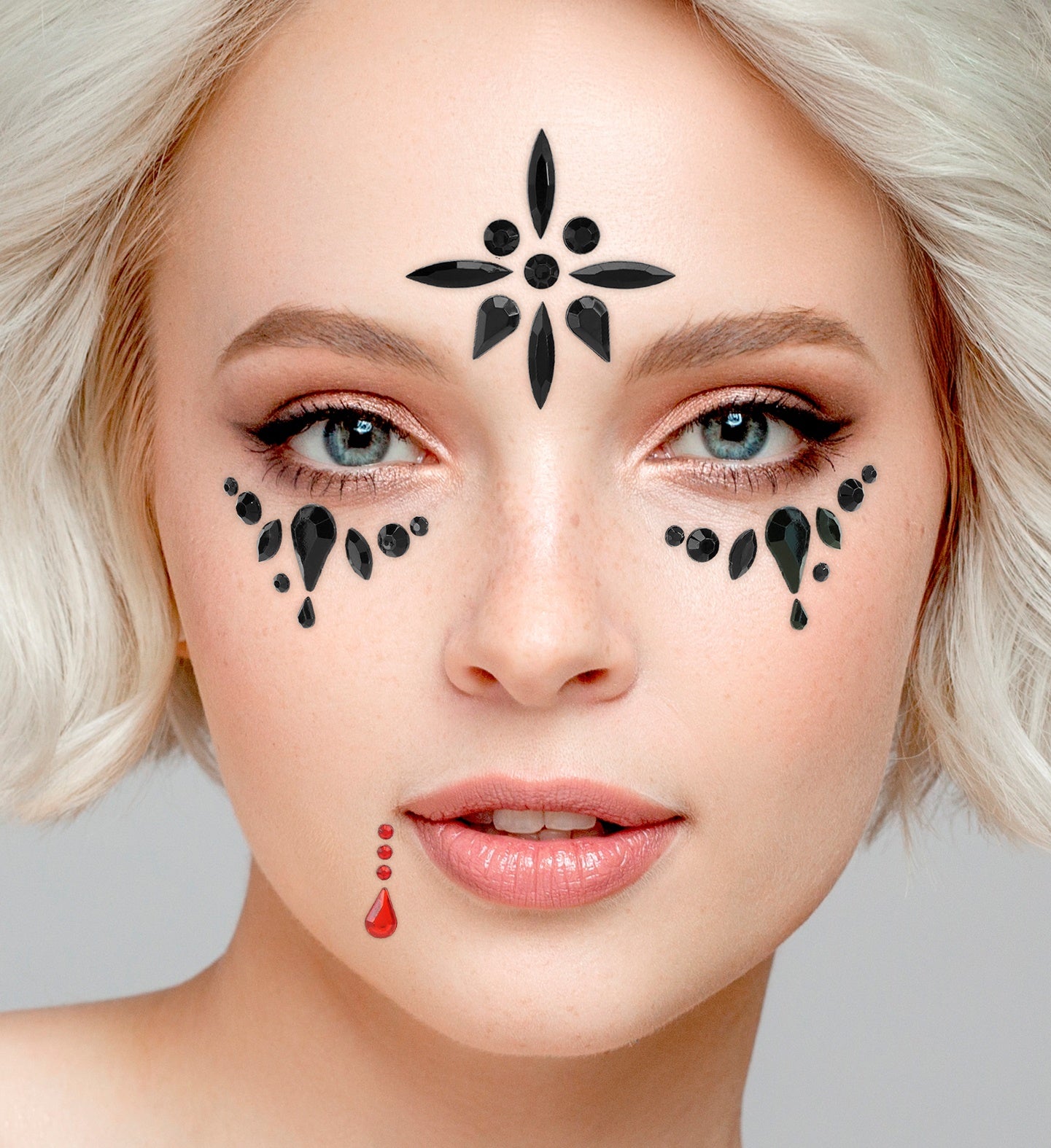 Close-up of black forehead and cheek face jewels paired with a red teardrop gem near the lips for a gothic costume.