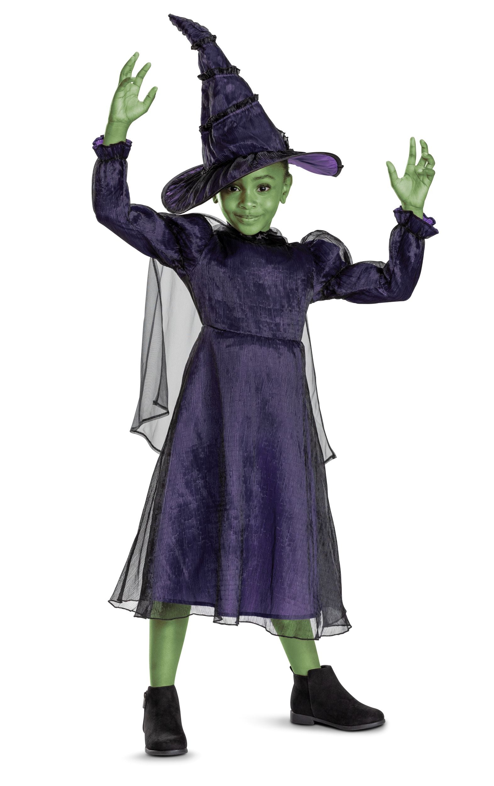 A child with green face paint poses in the full Elphaba witch costume, raising her hands to cast a spell.