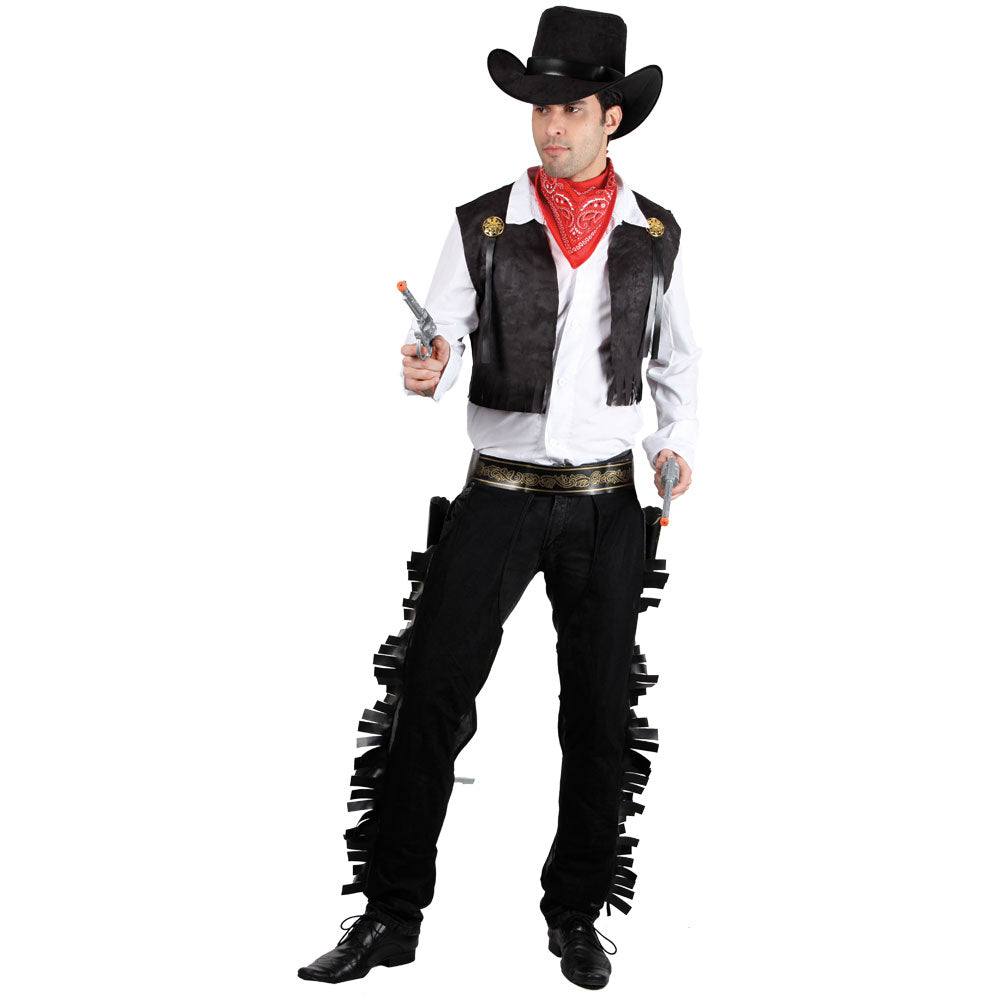 A male model wearing a classic Wild West cowboy fancy dress costume, featuring a black hat, red bandana, black fringed waistcoat with gold badges, and matching fringed chaps worn over dark trousers, posing with toy silver revolvers.