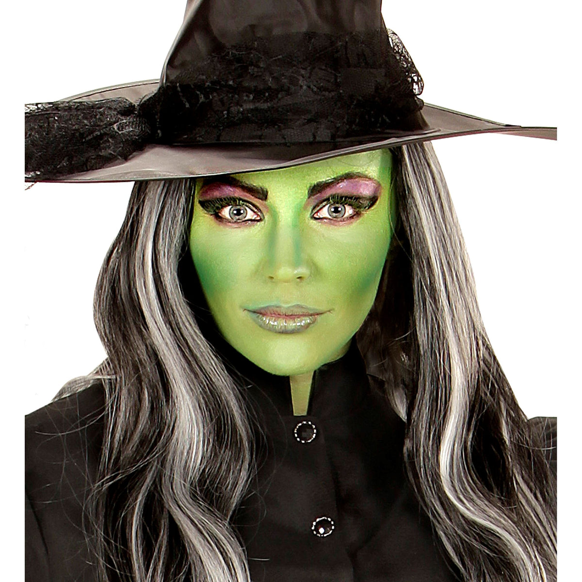 A glamorous adult witch look featuring a woman with a smooth green face makeup base, dramatic eye makeup, long silver and black hair, and a pointed black witch hat.