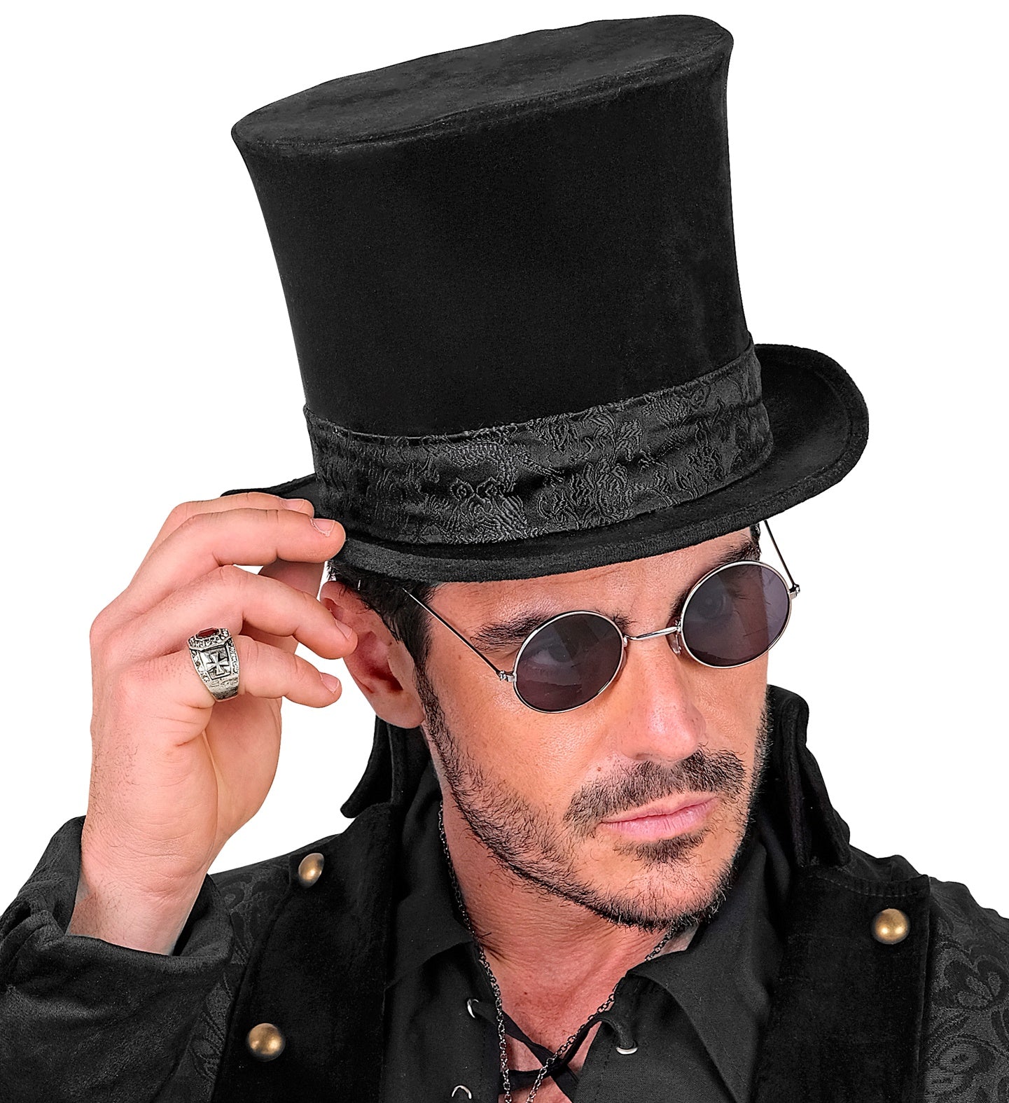 A man wearing a black velvet top hat with a decorative black band, black sunglasses, and a black costume jacket, holding the side of the hat with his hand against a white background.