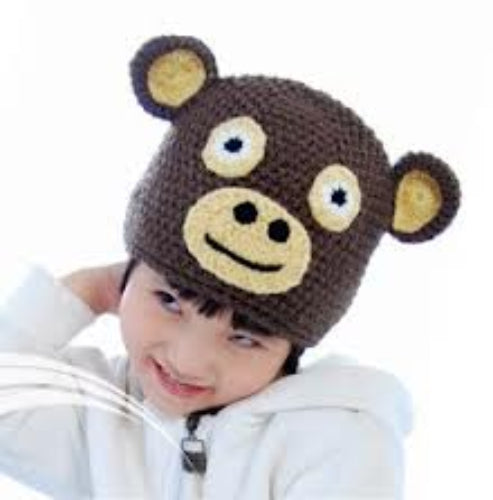 Child wearing a brown knitted hat with bear ears and eyes.